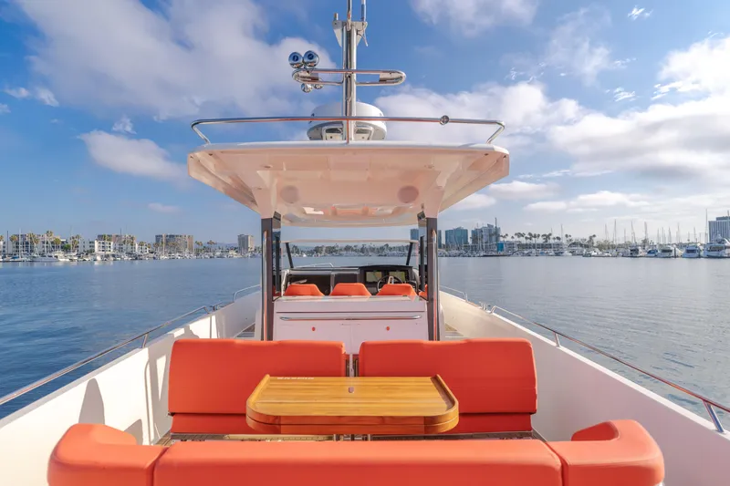 Intrepid Yacht Photos Pics Luxurious 2021 Nimbus T11 yacht with orange seating, docked in a scenic marina.