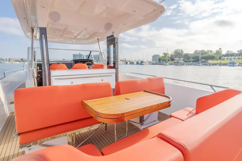 Intrepid Yacht Photos Pics Luxurious 2021 Nimbus T11 yacht with orange seating and wooden table, docked by the marina.