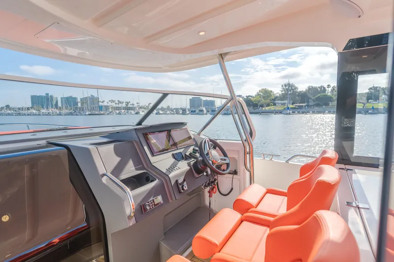 Intrepid Yacht Photos Pics Interior of 2021 Nimbus T11 boat with orange seats and modern dashboard, overlooking marina.