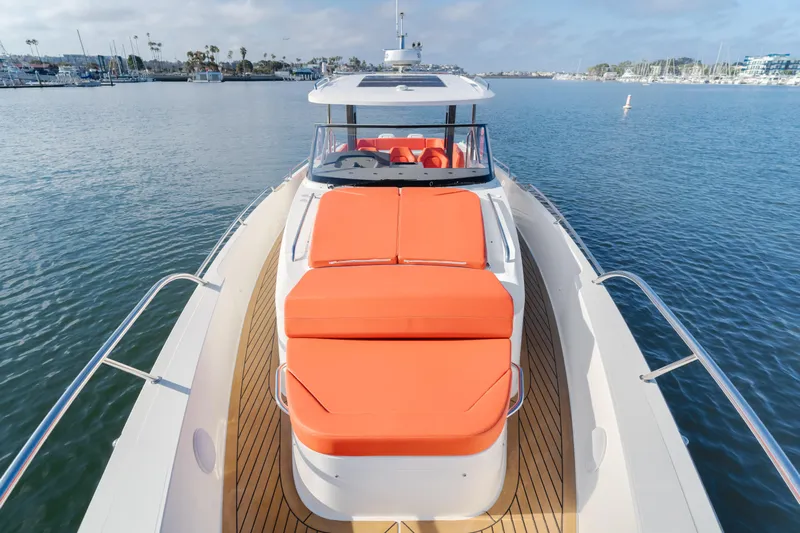 Intrepid Yacht Photos Pics Luxury Nimbus T11 yacht with orange sunbeds on deck, cruising in a serene marina.