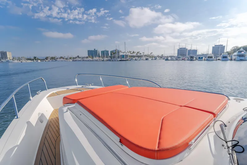 Intrepid Yacht Photos Pics Luxurious 2021 Nimbus T11 yacht with orange sunbed, docked in a scenic marina.