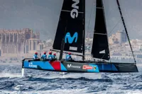 Sailing team racing GC 32 catamaran near coastal city, 2012 model.
