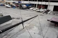 Boatyard with various sailboats and a GC 32 mast, 2012 model, in a storage area.