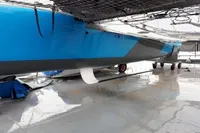 Blue and gray GC 32 catamaran from 2012 on a wet surface, underside view.