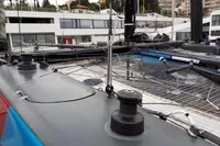 Sailboat deck with winches and rigging, GC 32 model, 2012, docked near modern buildings.