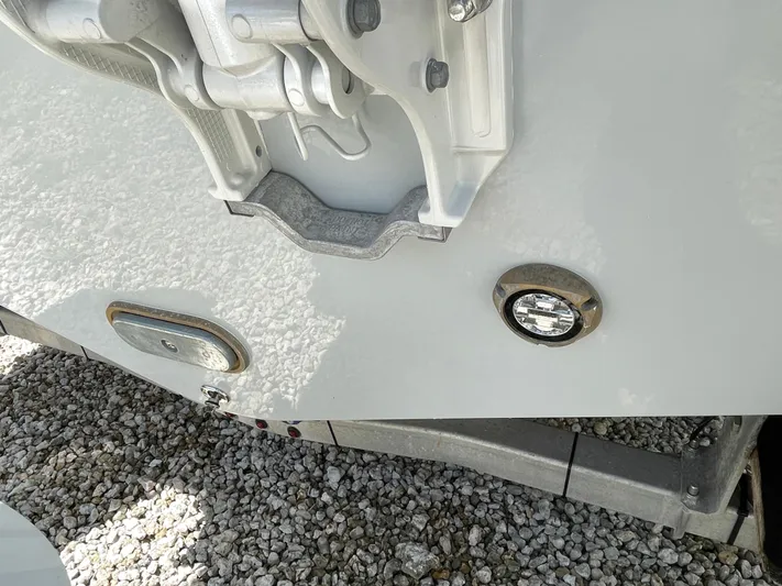 Whisper Gray Yacht Photos Pics 2025 Everglades 315 Center Console boat detail on gravel, showcasing hull and fittings.