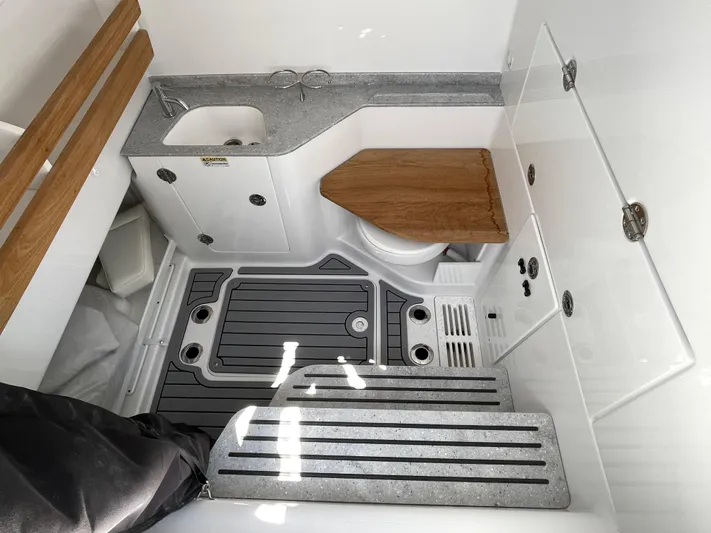 Whisper Gray Yacht Photos Pics 2025 Everglades 315 Center Console boat interior with sink, toilet, and wooden accents.