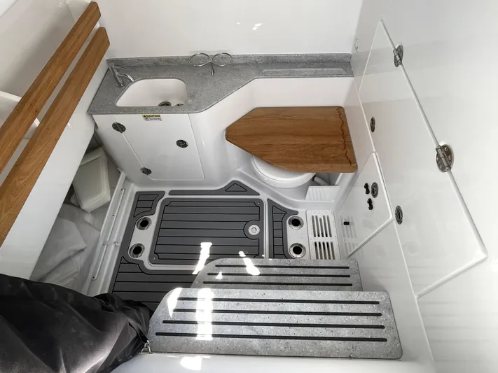 Whisper Gray Yacht Photos Pics 2025 Everglades 315 Center Console boat interior with sink, toilet, and wooden accents.