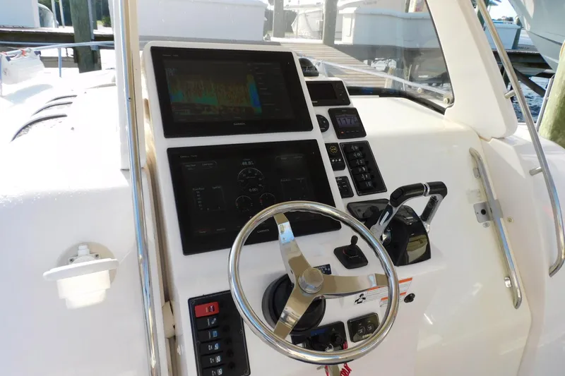 Happily Ever After Yacht Photos Pics Control panel of a 2016 Belzona 327 WA boat with steering wheel and navigation screens.