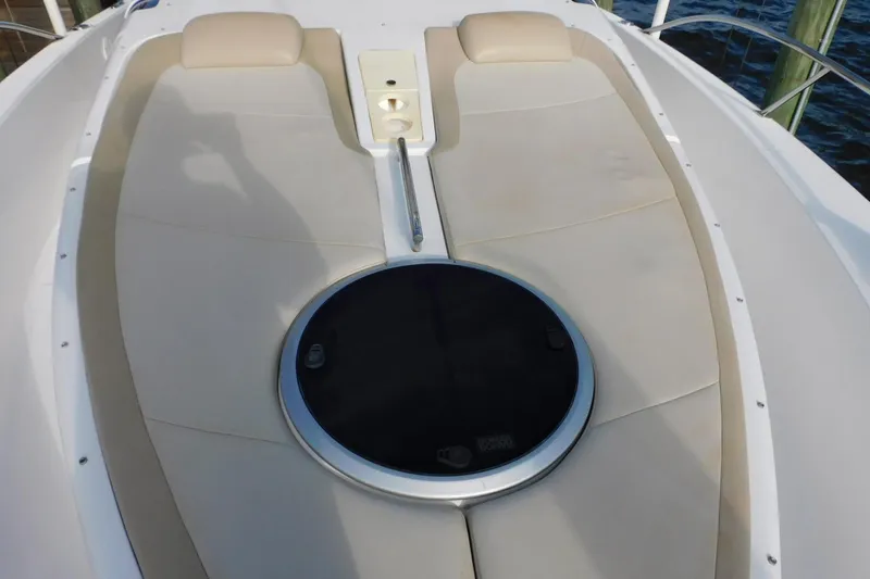 Happily Ever After Yacht Photos Pics Bow seating area on a 2016 Belzona 327 WA boat, featuring beige cushions and a circular hatch.