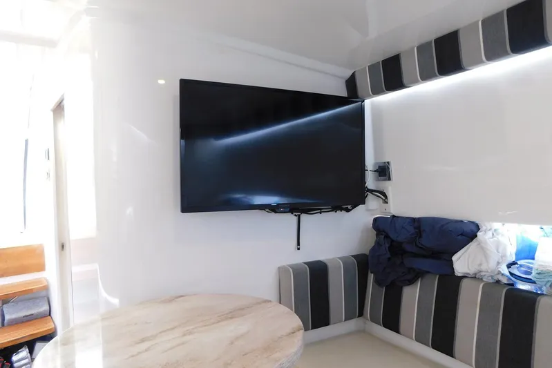 Happily Ever After Yacht Photos Pics Interior of 2016 Belzona 327 WA with mounted TV and striped seating.