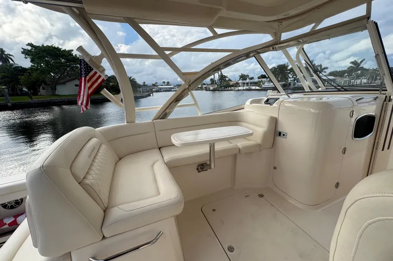 Texas Crewed Yacht Photos Pics 2024 Grady-White Freedom 335 boat interior with seating and table, docked by a scenic waterfront.