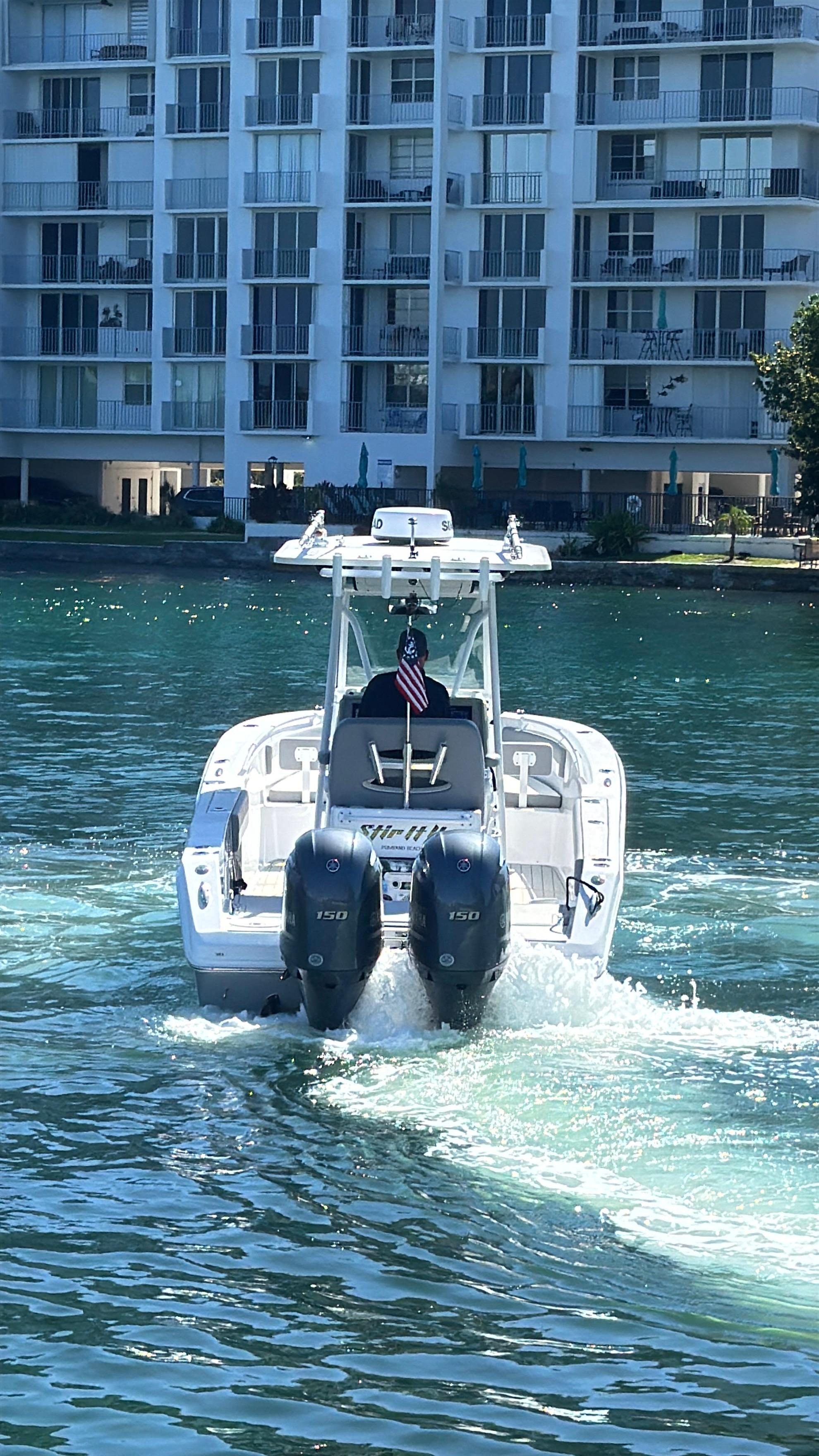A 2021 Release 240 RX boat cruising on water near modern waterfront buildings.
