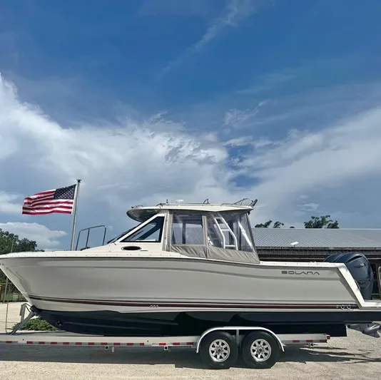 Yacht Photos Pics 2023 Solara S-310 CW boat on trailer with American flag and cloudy sky.