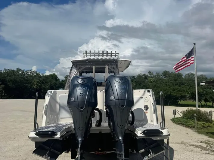  Yacht Photos Pics 2023 Solara S-310 CW boat with dual outboard motors, American flag, and cloudy sky.