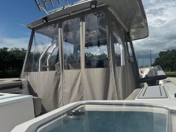  Yacht Photos Pics 2023 Solara S-310 CW boat with enclosed cabin, clear skies, and lush greenery.