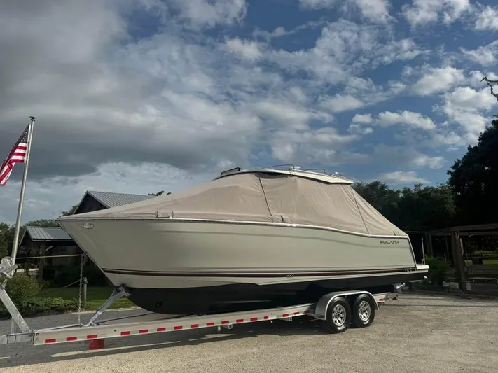  Yacht Photos Pics 2023 Solara S-310 CW boat on trailer, covered, with American flag nearby.