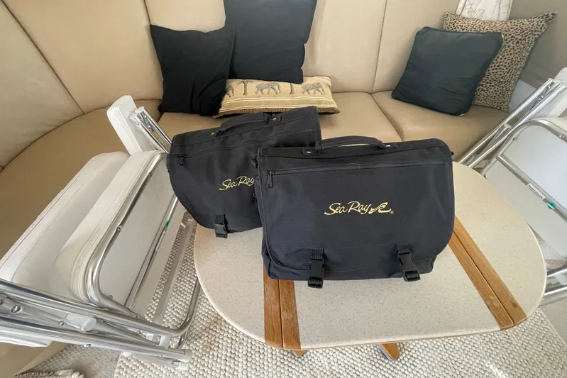 Double Kickback IV Yacht Photos Pics 1998 Sea Ray 480 Sedan Bridge interior with branded bags and folding chairs.