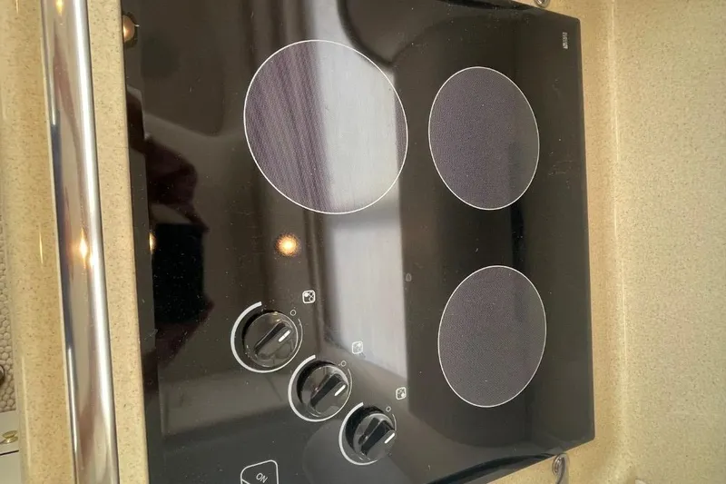 Double Kickback IV Yacht Photos Pics Stovetop on 1998 Sea Ray 480 Sedan Bridge yacht, featuring three burners and control knobs.