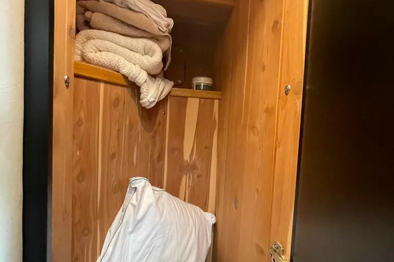 Double Kickback IV Yacht Photos Pics Wooden storage cabinet with folded towels and a pillow on a Sea Ray 480 Sedan Bridge.