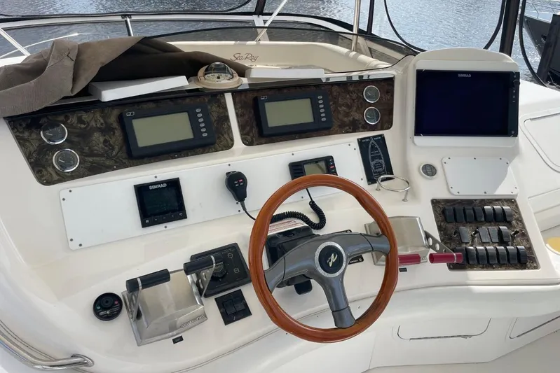 Double Kickback IV Yacht Photos Pics 1998 Sea Ray 480 Sedan Bridge helm with navigation instruments and wooden steering wheel.