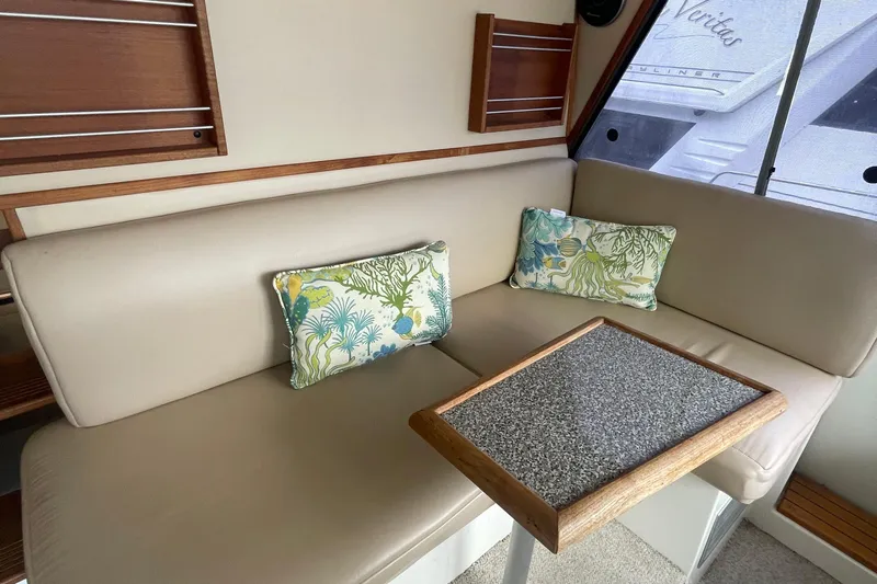  Yacht Photos Pics 1989 Bayliner Pilothouse 4588 interior with beige seating, decorative pillows, and a small table.