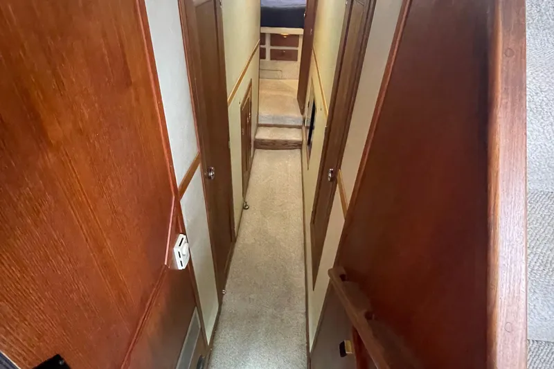  Yacht Photos Pics Narrow hallway inside 1989 Bayliner Pilothouse 4588, featuring wooden paneling and carpeted floor.