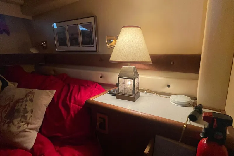  Yacht Photos Pics Cozy cabin interior of 1989 Bayliner Pilothouse 4588 with lamp and red bedding.