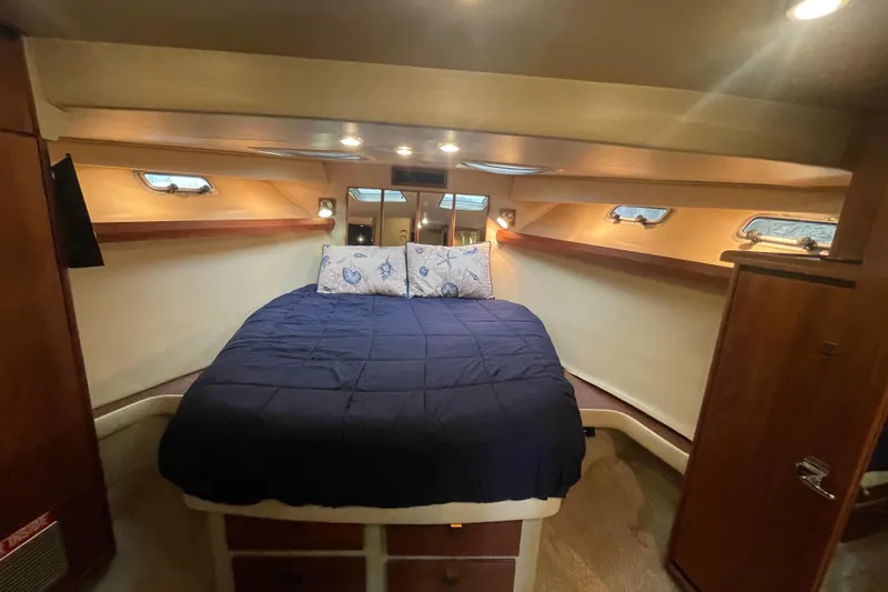  Yacht Photos Pics Cozy bedroom in 1989 Bayliner Pilothouse 4588 yacht with blue bedding and wooden accents.