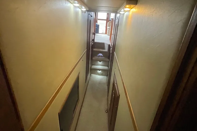  Yacht Photos Pics Narrow hallway inside 1989 Bayliner Pilothouse 4588 yacht, featuring carpeted stairs and ambient lighting.
