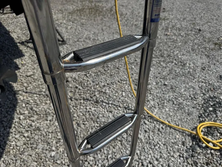 Max Dream Yacht Photos Pics Stainless steel boat ladder on 2014 Sea Ray 330 Sundancer, resting on gravel.