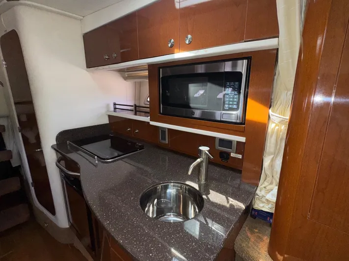 Max Dream Yacht Photos Pics 2014 Sea Ray 330 Sundancer galley with microwave, sink, and wooden cabinetry.