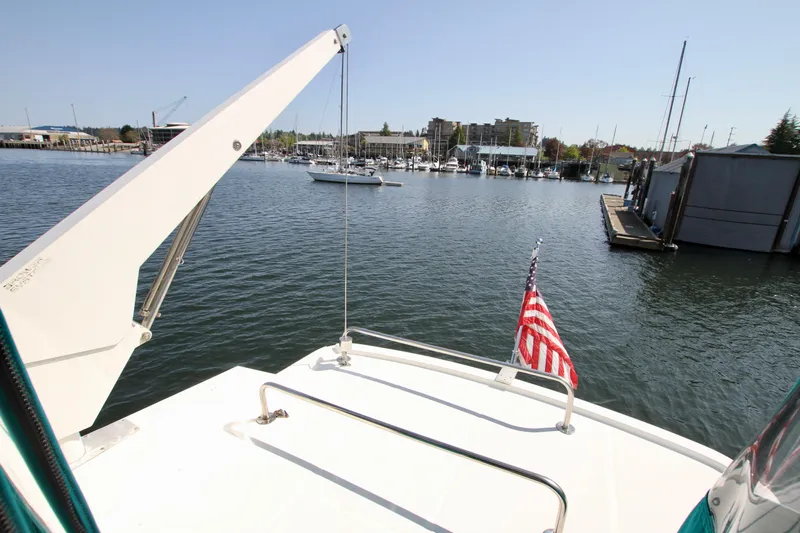  Yacht Photos Pics 1999 McKinna 47 Sedan yacht on calm waters with American flag, marina in background.