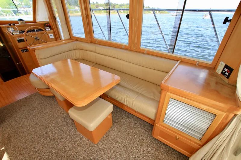  Yacht Photos Pics 1999 McKinna 47 Sedan interior with beige seating and wooden table by large windows.