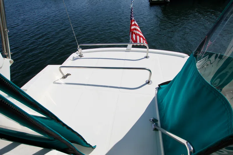  Yacht Photos Pics 1999 McKinna 47 Sedan yacht deck with American flag, teal accents, and railing.