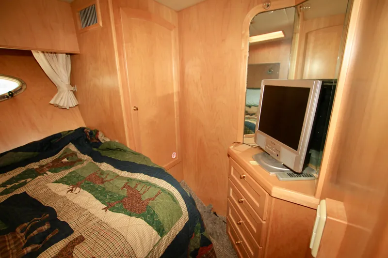  Yacht Photos Pics 1999 McKinna 47 Sedan cabin interior with bed, TV, and wooden cabinetry.