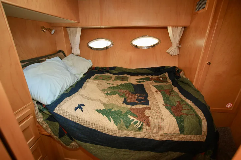  Yacht Photos Pics Cozy cabin bedroom in 1999 McKinna 47 Sedan yacht with quilted bedding and porthole windows.