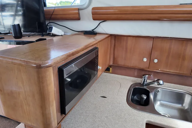  Yacht Photos Pics 2007 Cranchi Atlantique 40 yacht kitchen with microwave, sink, and wooden cabinetry.