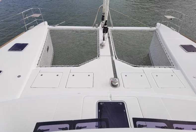 Er Yue Hua Hao Yacht Photos Pics 2014 Lagoon 620 catamaran deck with netting and storage compartments, docked on calm water.