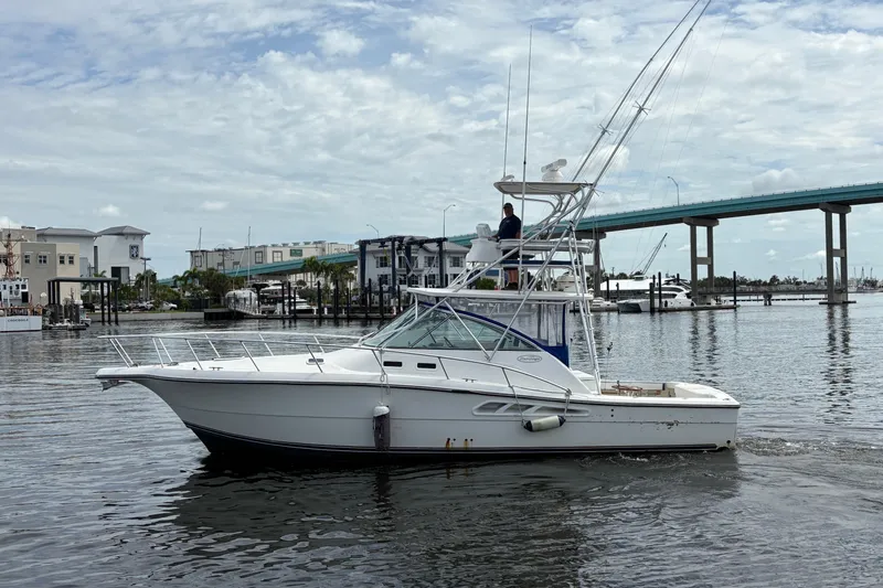 Free 2 Go Yacht Photos Pics 2006 Rampage 38 Express boat cruising near a marina with a bridge in the background.