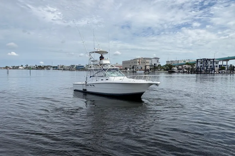 Free 2 Go Yacht Photos Pics 2006 Rampage 38 Express boat on calm water near a marina under a cloudy sky.