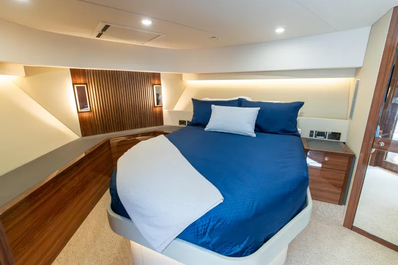 One More Yacht Photos Pics Luxurious 2024 Maritimo M55 yacht bedroom with elegant blue bedding and modern wood accents.