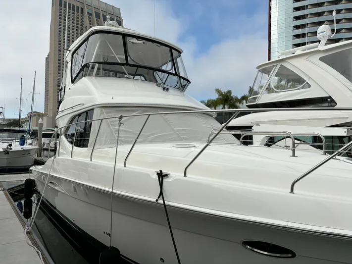  Yacht Photos Pics 2004 Silverton 38 Convertible yacht docked in marina, city skyline background.