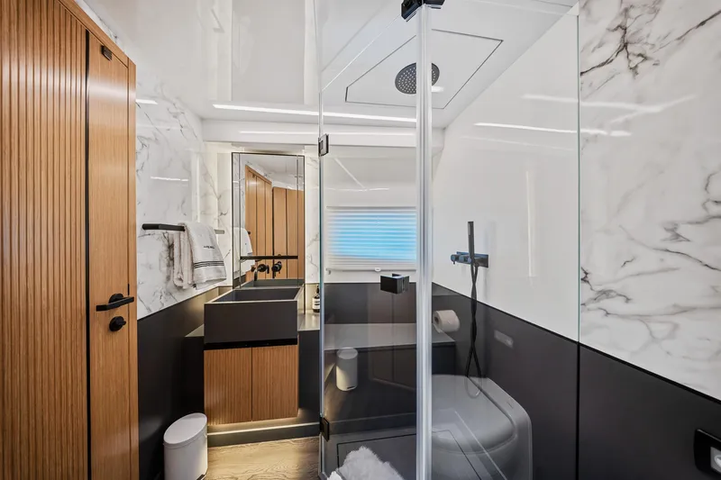 2023 Pearl 62 Luxury Yacht Yacht Photos Pics Modern yacht bathroom with marble walls, glass shower, and wooden accents in a 2023 Pearl 62.