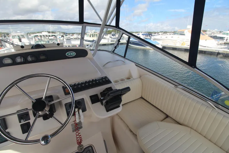 Karma Sea's Yacht Photos Pics 2001 Grady-White Express 330 boat cockpit with steering wheel, control panel, and marina view.