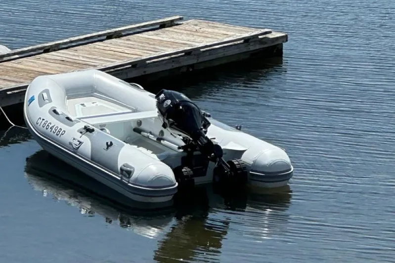 Free Range Yacht Photos Pics Inflatable boat docked on calm water, featuring an outboard motor.