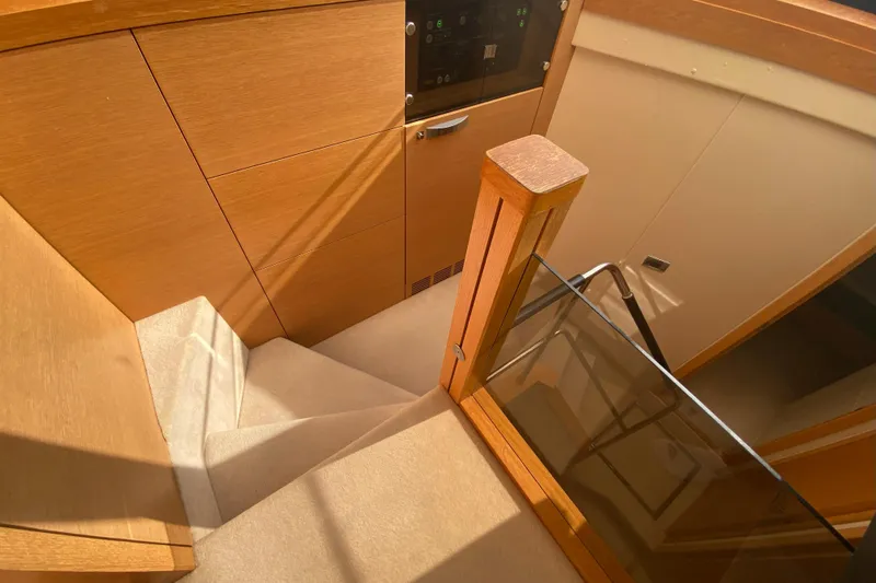 Nm01655 Yacht Photos Pics Interior staircase of 2011 Sunseeker Manhattan 63 yacht with wooden finish and glass railing.