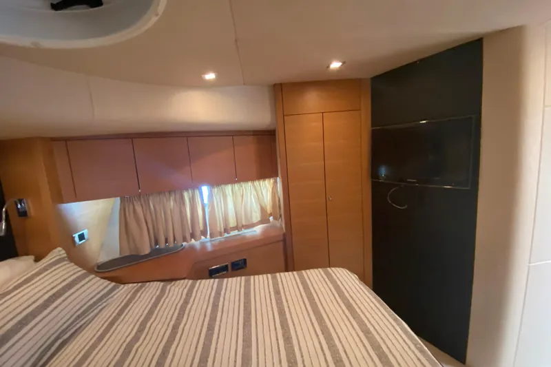 Nm01655 Yacht Photos Pics Interior of 2011 Sunseeker Manhattan 63 yacht bedroom with striped bedding and wall-mounted TV.