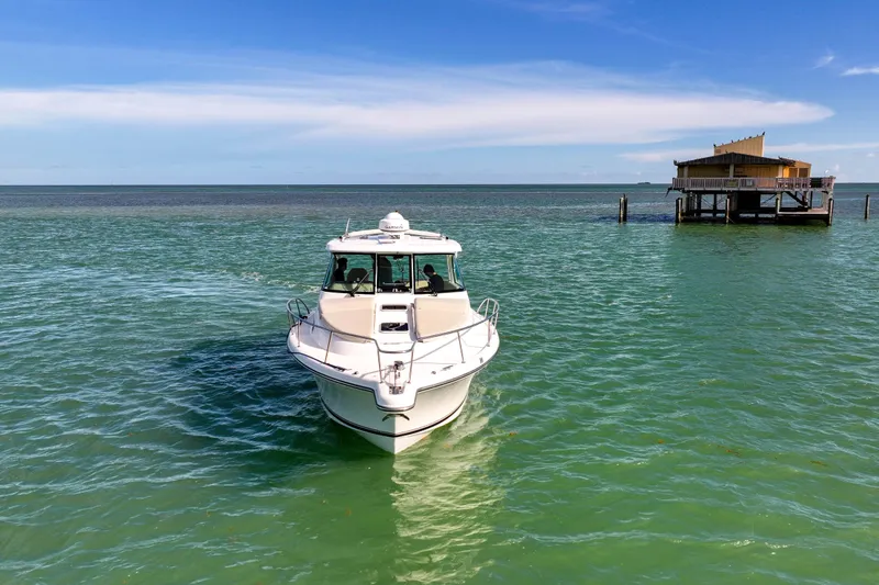  Yacht Photos Pics 2016 Pursuit OS 385 Offshore boat on turquoise water near a coastal structure.