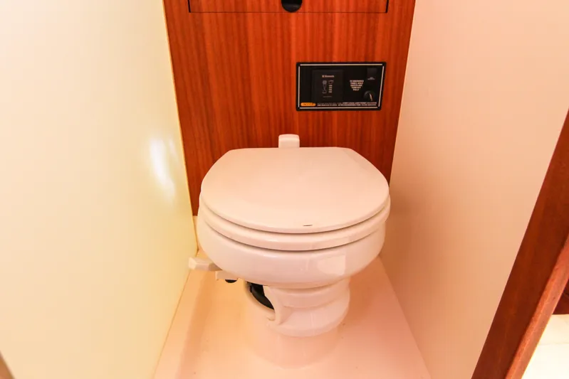 Yacht Photos Pics 2016 Pursuit OS 385 Offshore boat bathroom with a white toilet and wooden paneling.
